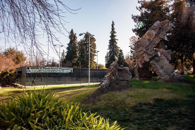 view of community featuring tennis court and a lawn