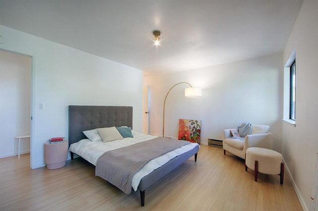 bedroom featuring a baseboard heating unit and light hardwood / wood-style flooring