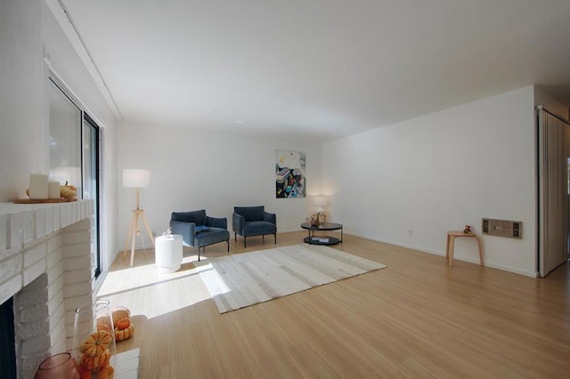 unfurnished room featuring light hardwood / wood-style floors and a brick fireplace