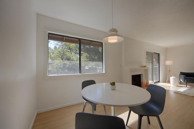 dining room with a brick fireplace and light wood-type flooring