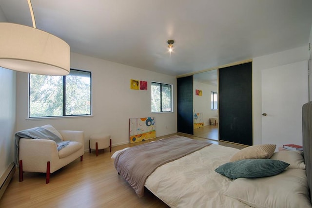 bedroom featuring baseboard heating and light hardwood / wood-style flooring