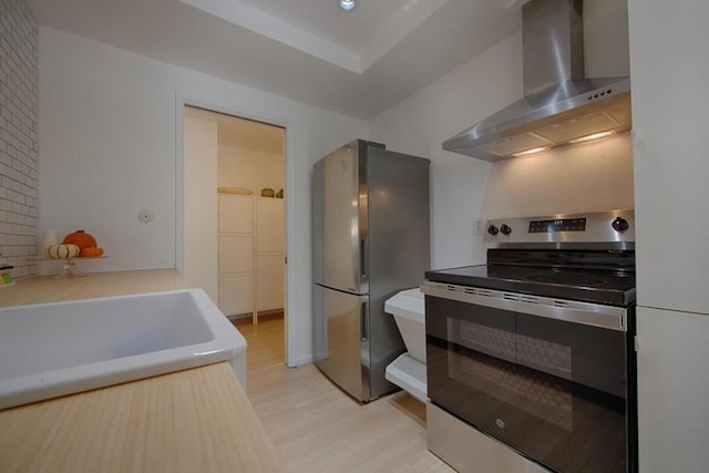 kitchen featuring wall chimney exhaust hood, stainless steel appliances, sink, and light hardwood / wood-style flooring