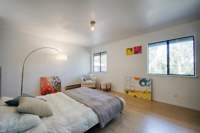 bedroom with light wood-type flooring and baseboard heating