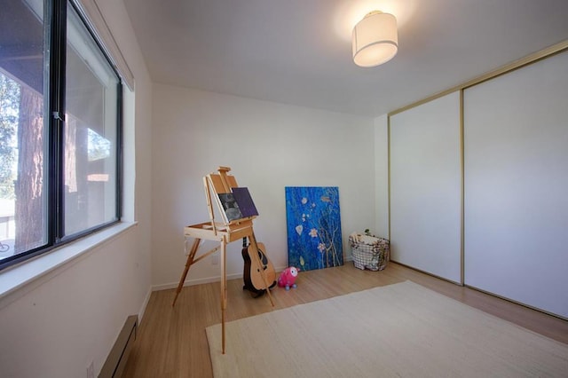 rec room featuring a healthy amount of sunlight, hardwood / wood-style floors, and a baseboard heating unit