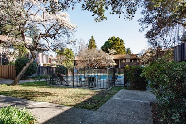 view of property's community with a swimming pool and a lawn