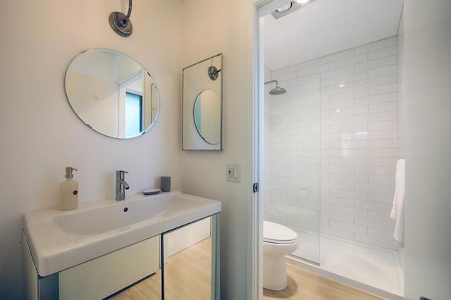 bathroom featuring hardwood / wood-style flooring, vanity, a shower with shower door, and toilet