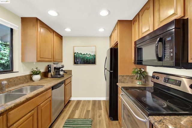 kitchen featuring light stone countertops, sink, light hardwood / wood-style flooring, and black appliances