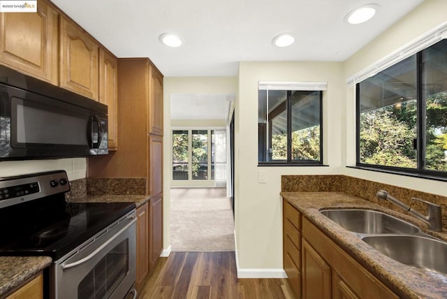 kitchen with electric stove, sink, dark hardwood / wood-style floors, and dark stone countertops