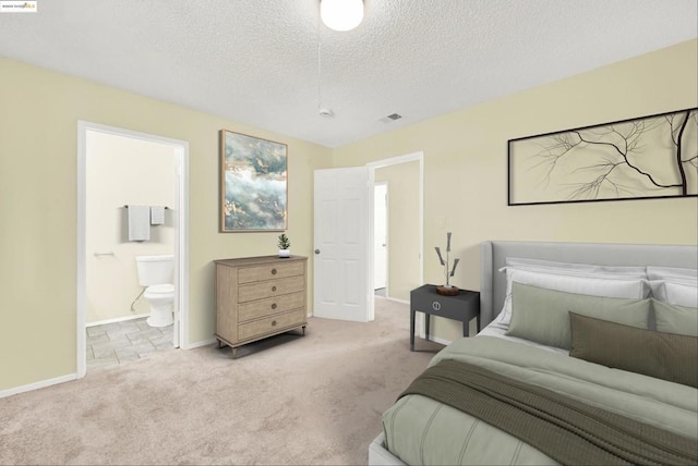 carpeted bedroom with ensuite bath and a textured ceiling