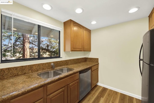 kitchen with sink, hardwood / wood-style flooring, stainless steel dishwasher, and black fridge