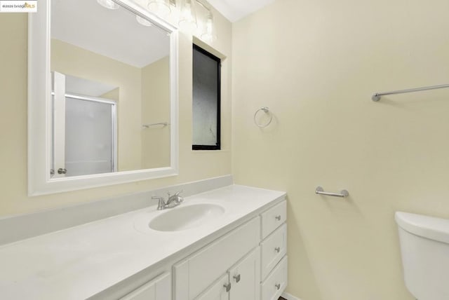 bathroom featuring vanity, a shower with shower door, and toilet