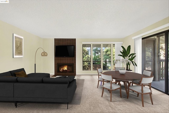 carpeted living room featuring a tiled fireplace and a textured ceiling