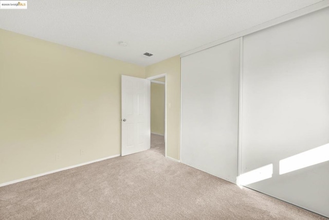 carpeted empty room featuring a textured ceiling