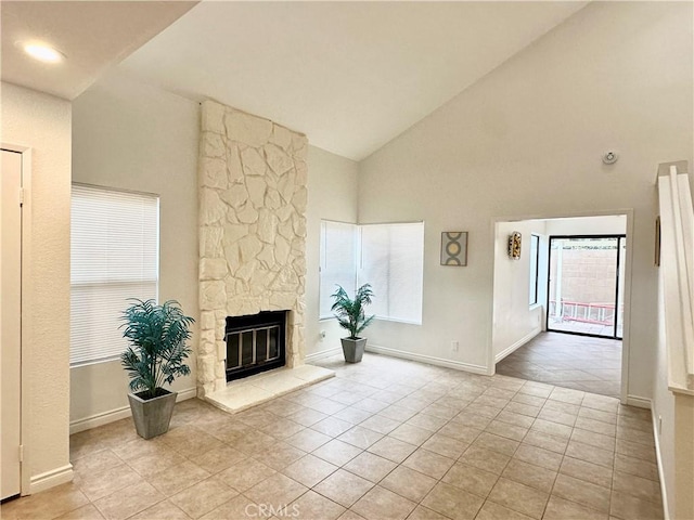 unfurnished living room with light tile patterned flooring, a stone fireplace, and high vaulted ceiling