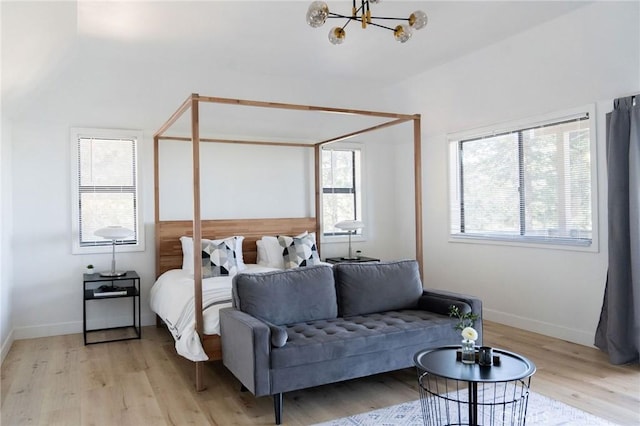 bedroom with multiple windows, an inviting chandelier, and light wood-type flooring