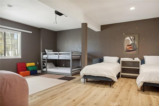 bedroom with light hardwood / wood-style flooring and beamed ceiling