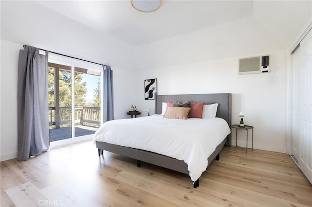 bedroom featuring access to exterior, a wall mounted AC, and light wood-type flooring