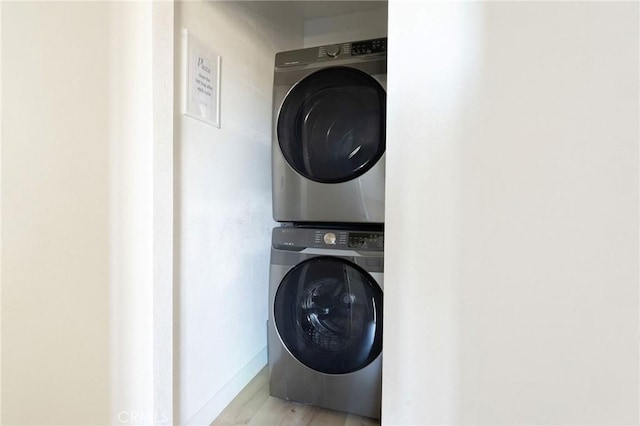 washroom featuring stacked washer and dryer and light hardwood / wood-style floors