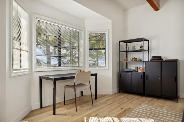 home office featuring light hardwood / wood-style floors and beamed ceiling