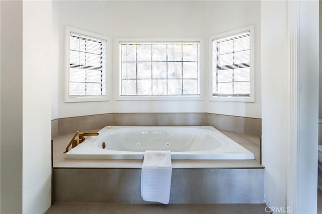 bathroom with toilet and tiled tub