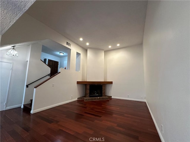 unfurnished living room featuring a brick fireplace and dark hardwood / wood-style floors