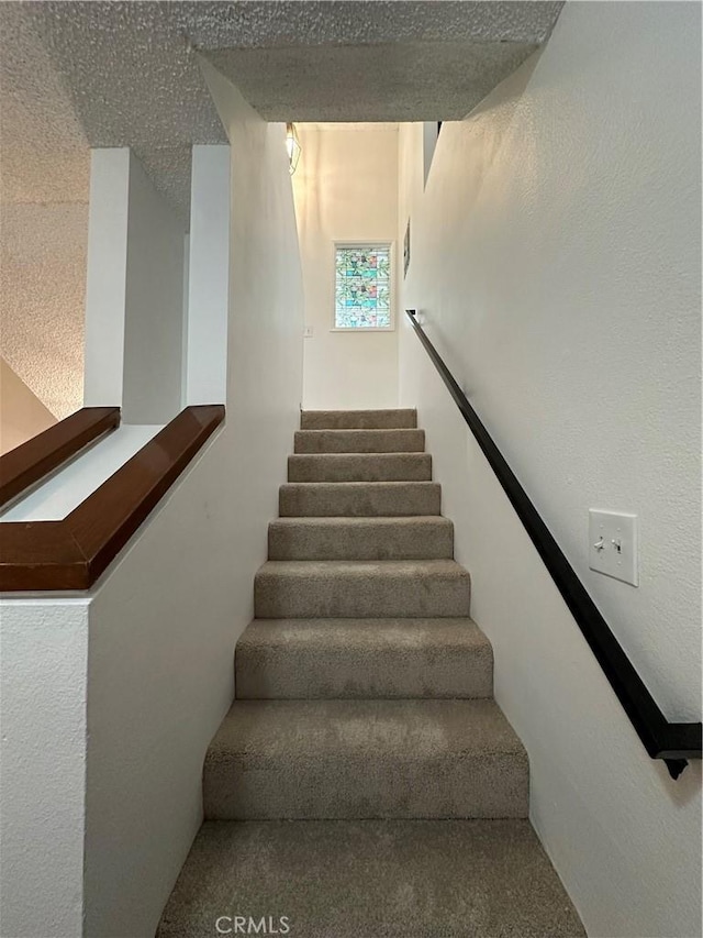 staircase featuring a textured ceiling