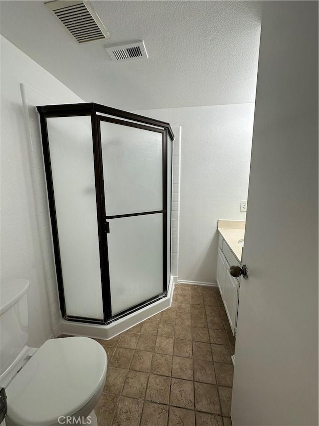 bathroom with vanity, toilet, a shower with shower door, and a textured ceiling