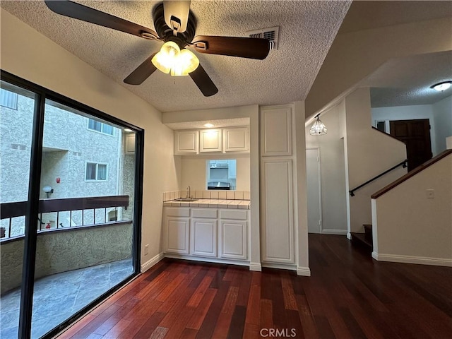 kitchen with dark hardwood / wood-style flooring, sink, tile countertops, and white cabinets