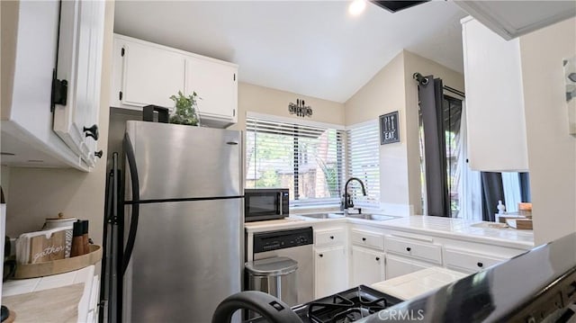 kitchen featuring appliances with stainless steel finishes, lofted ceiling, sink, white cabinets, and tile counters