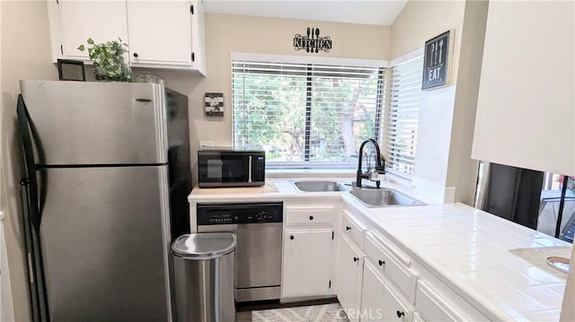 kitchen with stainless steel appliances, tile countertops, sink, and white cabinets