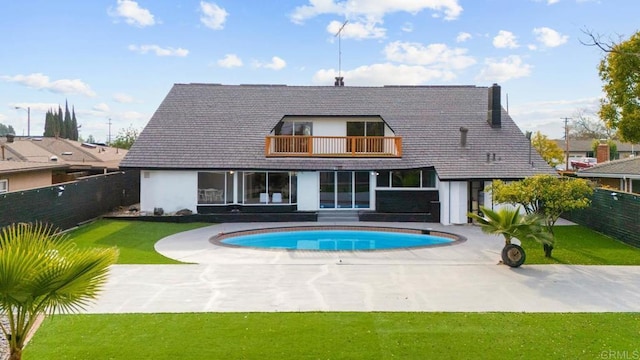 rear view of property featuring a balcony, a yard, a fenced in pool, and a patio