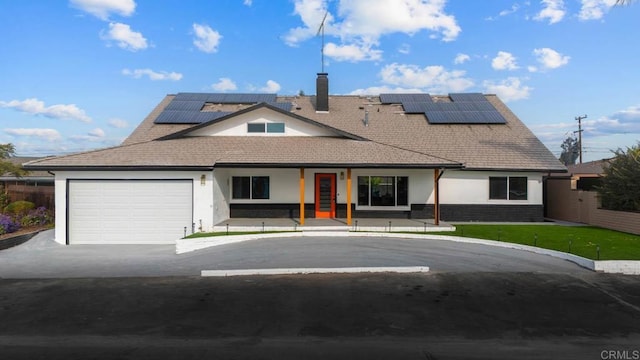 view of front facade featuring a garage, a front lawn, and solar panels