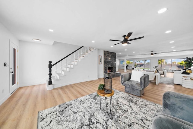 living room with ceiling fan, a fireplace, and light hardwood / wood-style flooring