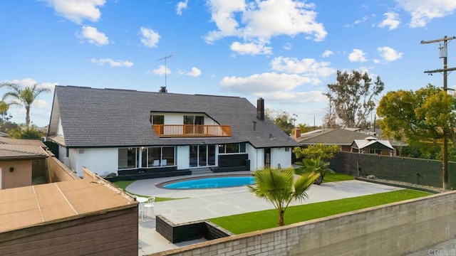 rear view of property featuring a fenced in pool, a balcony, and a patio area