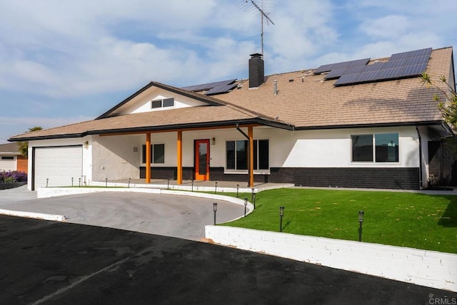 view of front of home featuring a garage, a front yard, and solar panels