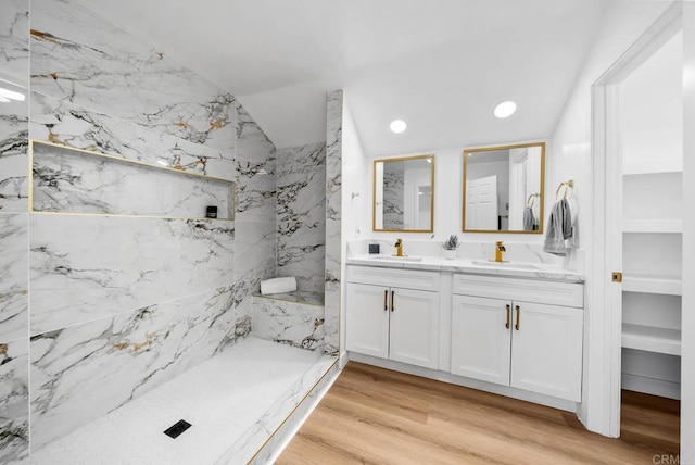 bathroom featuring lofted ceiling, vanity, hardwood / wood-style floors, and a tile shower