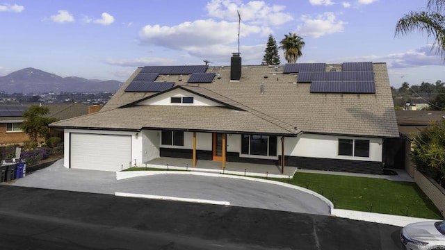 view of front of house with a mountain view, a garage, and solar panels