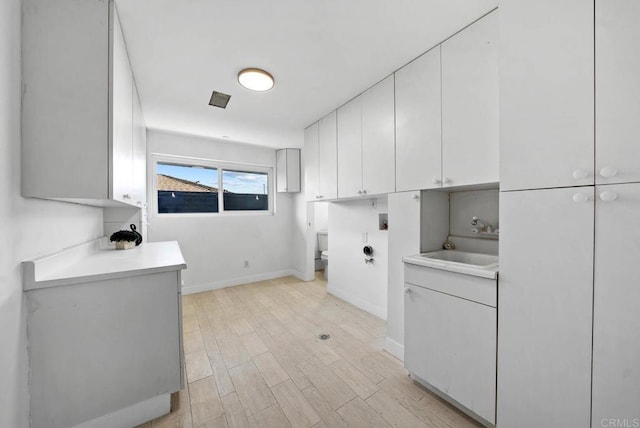 laundry room featuring cabinets, sink, hookup for an electric dryer, and light hardwood / wood-style flooring