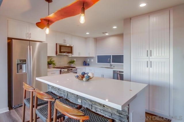 kitchen featuring hanging light fixtures, white cabinetry, appliances with stainless steel finishes, and a center island