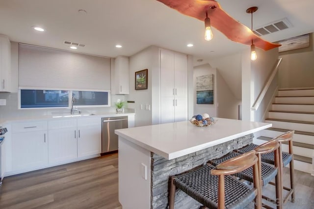 kitchen with sink, decorative light fixtures, stainless steel dishwasher, a kitchen island, and white cabinets