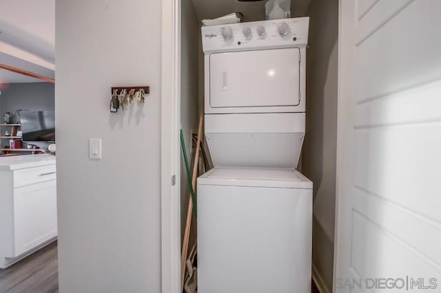 laundry area with stacked washer and dryer and light wood-type flooring