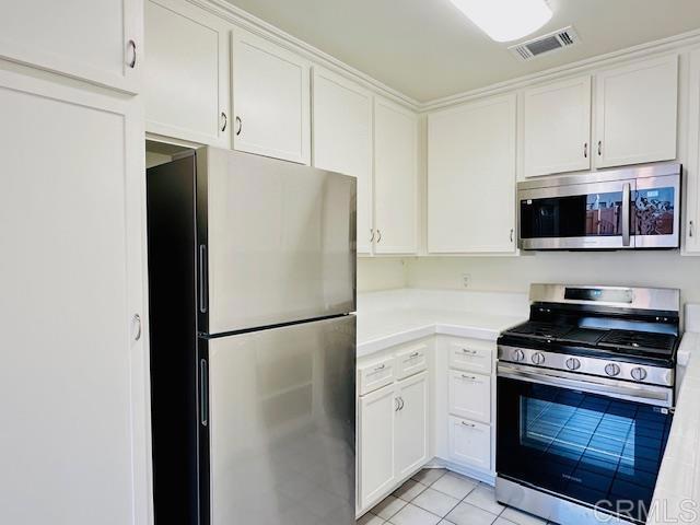 kitchen featuring light tile patterned floors, stainless steel appliances, and white cabinets