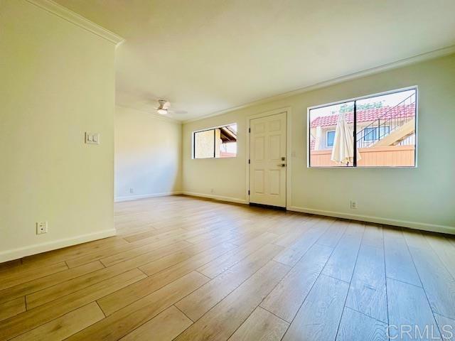 empty room with crown molding, ceiling fan, and light hardwood / wood-style floors