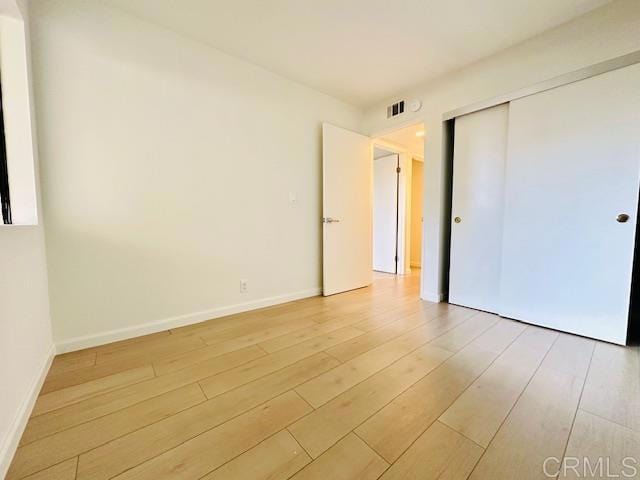 unfurnished bedroom featuring light wood-type flooring and a closet