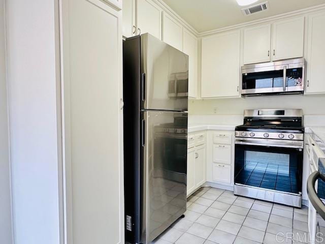 kitchen with light tile patterned floors, stainless steel appliances, and white cabinets