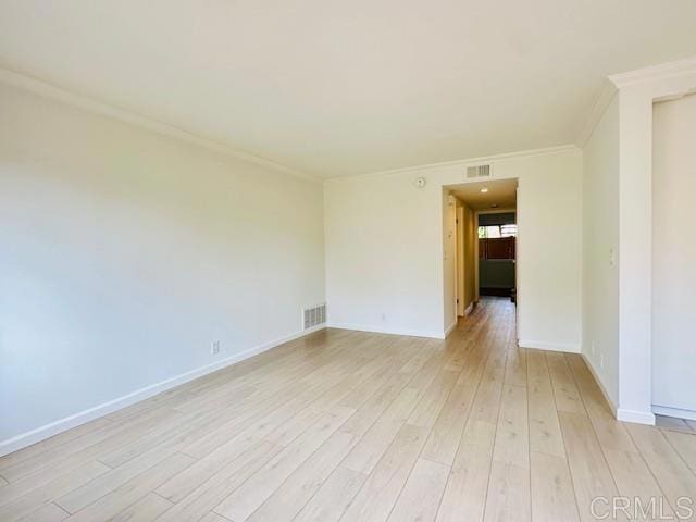 empty room with crown molding and light hardwood / wood-style floors