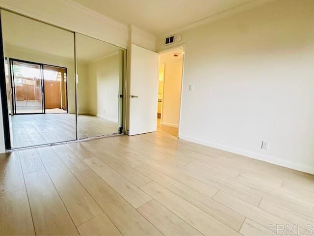 unfurnished bedroom featuring a closet, ornamental molding, and light hardwood / wood-style flooring