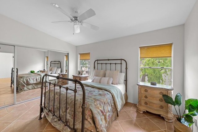 tiled bedroom featuring multiple windows, vaulted ceiling, ceiling fan, and a closet