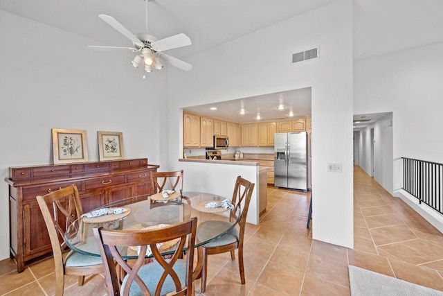 tiled dining area with ceiling fan and high vaulted ceiling