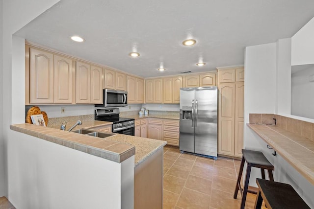 kitchen featuring sink, light tile patterned floors, a breakfast bar area, stainless steel appliances, and kitchen peninsula